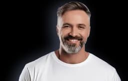 Portrait of a man aged 45-55 with salt and pepper hair and beard wearing a white t-shirt